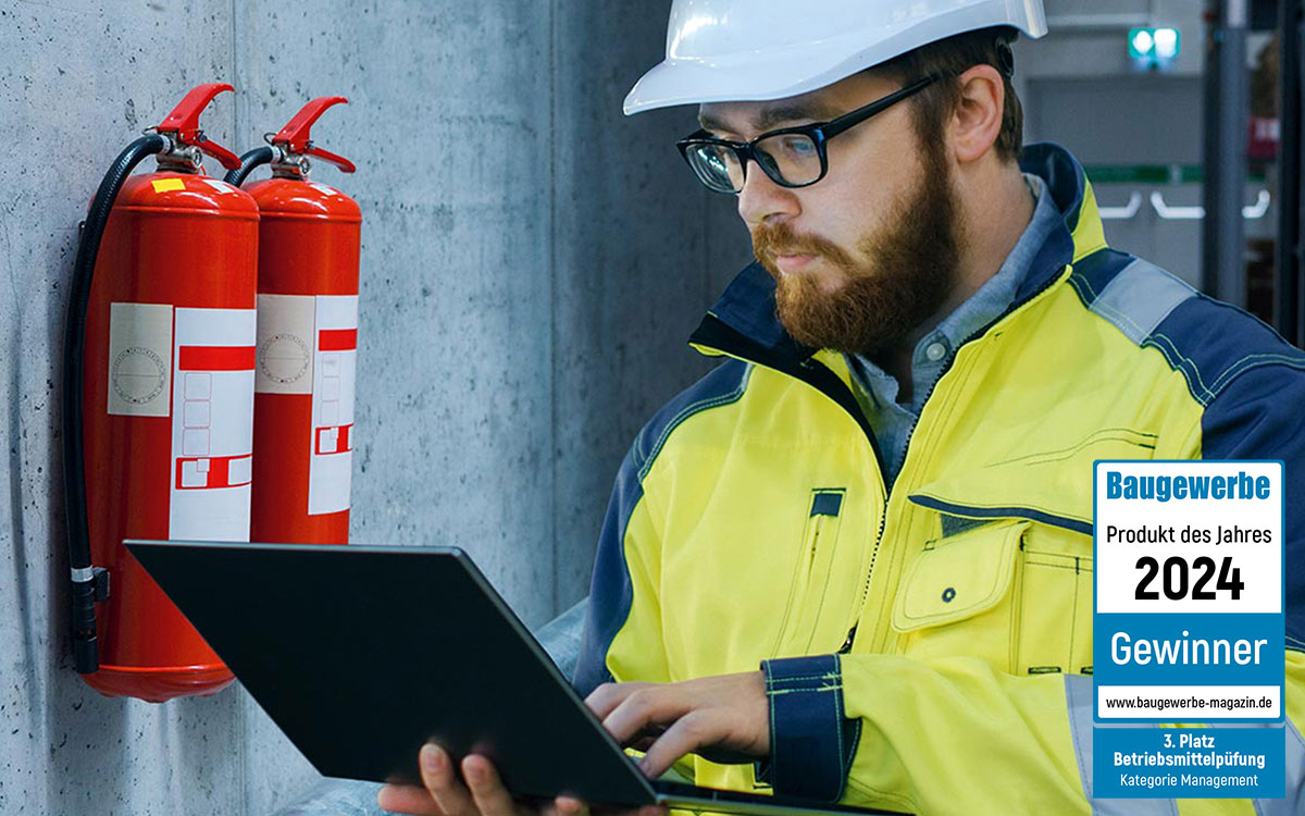 Prüfer steht vor Feuerlöschern und macht eine Betriebsmittelprüfung.