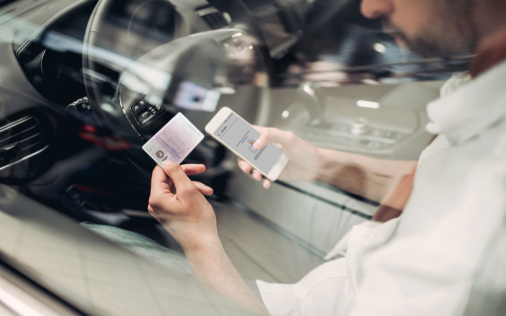 Person liest einen NFC-Transponder auf einem Führerschein mit dem Smartphone aus.
