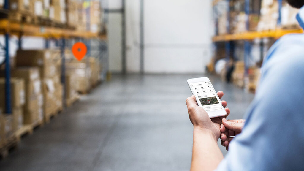 Softwarelösung Assetmanager Lagerhalle mit verschiedenen Assets und Smartphone mit der App Assetmanager.